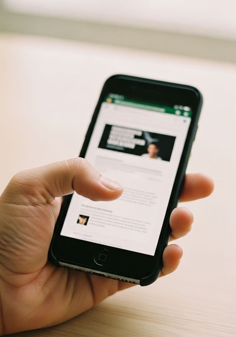 Smartphone in mano che mostra un sito vecchio e difficile da leggere